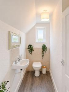 a white bathroom with a toilet and a sink at Marine Parade - Beach Apartment in Southtown