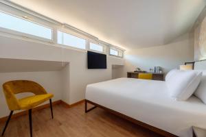 a bedroom with a large white bed and a yellow chair at Hotel Castello in LʼAquila