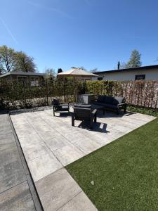 a patio with benches and an umbrella and grass at Knus chalet Heidebloem Recreational purposes only in Putten