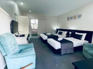 a hotel room with two beds and a couch at Legends Motel in Palmerston North