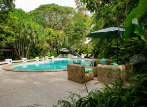 a swimming pool with wicker chairs and an umbrella at Nawa Wellness in Calatagan