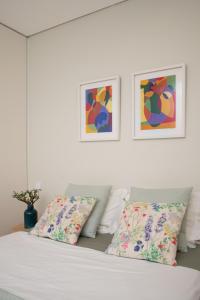 a white bedroom with a bed with pillows and paintings at Allegro Patio House in Porto