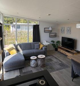 a living room with a couch and a flat screen tv at Knus chalet Heidebloem Recreational purposes only in Putten