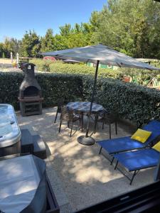 a patio with a table and chairs and an umbrella at Des roulottes en Provence in Barbentane