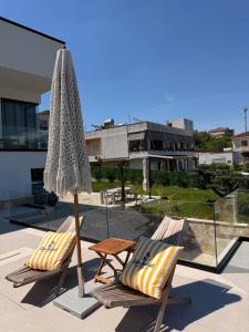 two lounge chairs and an umbrella on a patio at Vog Villa in Tirana
