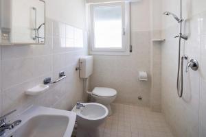 a white bathroom with a toilet and a sink at Residenza Stella Y in Bibione +10 photos