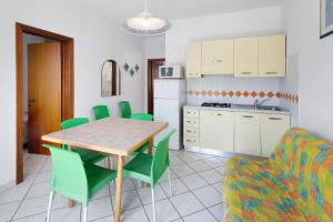 a kitchen and dining room with a table and green chairs at Residenza Stella Y in Bibione