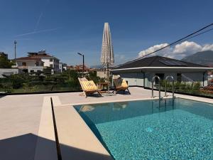 a swimming pool with two chairs and a table at Vog Villa in Tirana
