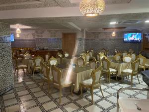 a dining room with tables and chairs and a tv at Hotel Almas Meknes in Meknès