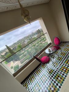 a room with a large window with a table and chairs at Hotel Almas Meknes in Meknès