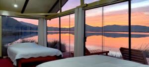 a room with two beds and a view of a lake at Titicaca Uros Atardecer in Puno