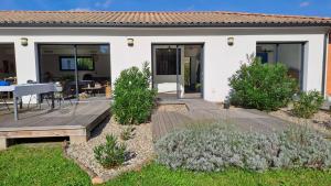 a house with a wooden deck in the yard at Maison GINKGO in Hourtin