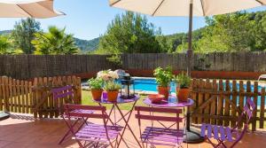 a patio with purple chairs and an umbrella and a table with plants at Villa Sitges El Olivo High Comodity AC Pool Heated 30º Optional Real Garden Pool XXL 10 min drive from Sitges in Olivella