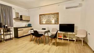 a living room with a table with chairs and a television at Appartamento Osnao in Cefalù