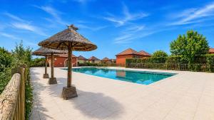 a swimming pool with an umbrella and a house at Élégant T3 avec terrasse & piscine et parking in Prayssac