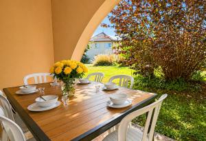 a wooden table with chairs and a vase of flowers at Élégant T3 avec terrasse & piscine et parking in Prayssac