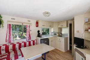 a kitchen with a wooden table and red chairs at Mobilehome chez dede in Porto-Vecchio
