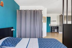 a bedroom with a bed with blue walls and a curtain at Le Cabano'scope in Chasseneuil-du-Poitou
