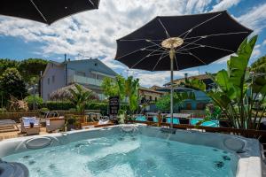a hot tub with an umbrella and some chairs at CASA MAJOR Appartamenti in Cervia