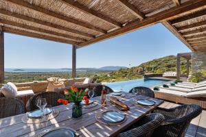 a dining table and chairs with a view of a pool at Villa Schena Villata in Zonza