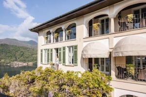 a building with windows and a lake in the background at Villa Antica Colonia SPA & Wellness in Pettenasco