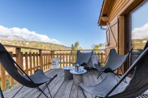a porch with two chairs and a table on a deck at Chalet le 22 Agniéres in Le Dévoluy