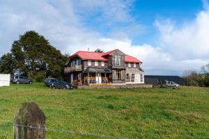 a large house with a red roof in a field at Refugio del Sur, Escapada in Llanquihue