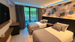 a hotel room with two beds and a window at Hotel LUHA in Puerto Varas