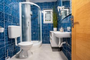 a blue tiled bathroom with a toilet and a sink at Apartmani IVA in Neum