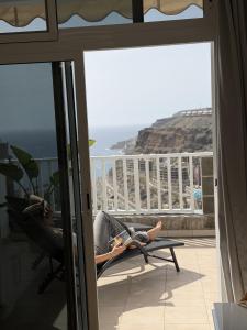 a person laying in a chair reading a book on a balcony at AMADORES BEACH VIEW APARTMENT in Amadores
