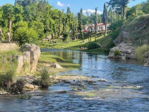 a river with people sitting on the side of it at Cabañas Del Sol in Trapiche