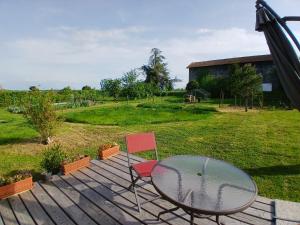 Ein Glastisch und ein Stuhl auf einer Holzterrasse in der Unterkunft La Contesse in Masseube