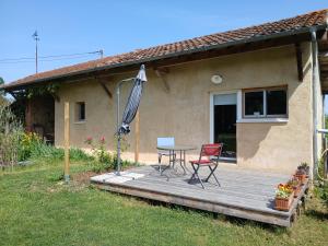 eine Holzterrasse mit Tisch, Stühlen und Sonnenschirm in der Unterkunft La Contesse in Masseube