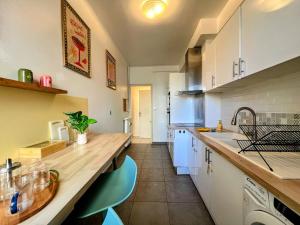 a kitchen with white cabinets and a wooden counter top at Évasion azuréenne - balcon, confort à Nice in Nice +24 photos