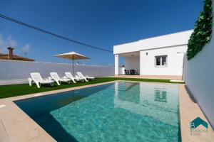 a swimming pool in front of a house at Ginebra A BARROSAHOME in Novo Sancti Petri