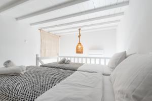 a white bedroom with two white beds and a chandelier at White Pearl Mykonos in Mikonos