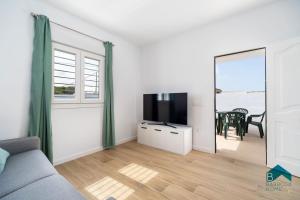 a living room with a couch and a tv and a table at Ginebra A BARROSAHOME in Novo Sancti Petri