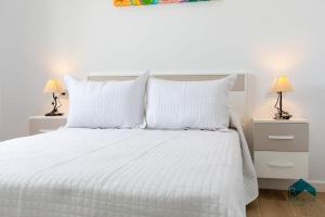 a white bed with white pillows and two lamps at Ginebra A BARROSAHOME in Novo Sancti Petri +24 photos