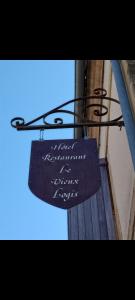 a sign hanging from the side of a building at Hôtel Restaurant Le Vieux Logis in Aignan