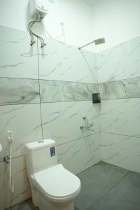 a bathroom with a white toilet and marble walls at Dune Hostel - Dune Homestay in Alleppey +14 photos
