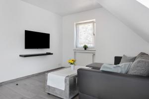 a living room with a couch and a tv on a wall at Seetraum Berger in Hagnau