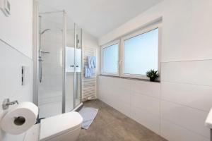 a white bathroom with a toilet and a shower at Seetraum Berger in Hagnau +28 photos