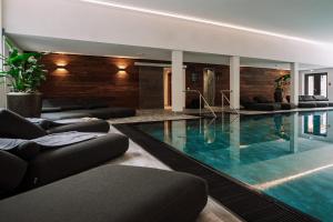 a swimming pool with couches and chairs in a building at Allgäuer Bergwald Chalets in Oberstaufen