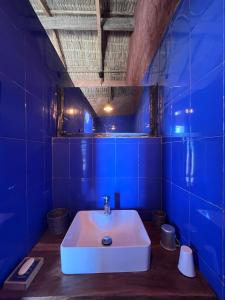 a bathroom with a white sink in a blue room at Mbin Maak du Saloum in Mar Lodj