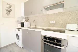 a white kitchen with a sink and a dishwasher at Little Paradise in Castro Marim