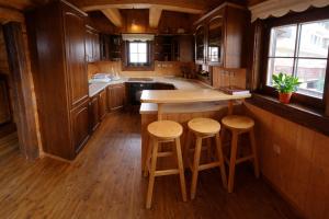 a kitchen with wooden cabinets and a island with stools at Zrub u Zuzany in Lazy pod Makytou