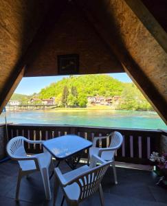 a table and chairs on a balcony with a view of the water at Alfa in Kulen Vakuf
