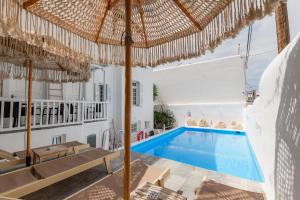 a villa with a swimming pool and an umbrella at White Pearl Mykonos in Mikonos