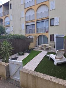 a building with a yard with a chair and a bench at Appartement T2 avec son rez de jardin de 40 m2 5 couchages 250m de la plage et 15km de l'Arena in Narbonne-Plage