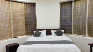 a bedroom with a bed with white sheets and windows at Rajvin Heavens Resort in Bhīm Tāl